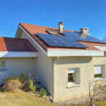 Maison autonome en énergie : vue de la façade avec les panneaux solaires et la pompe à chaleur.